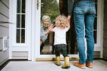 Little girl visits grandmother on other side of glass door